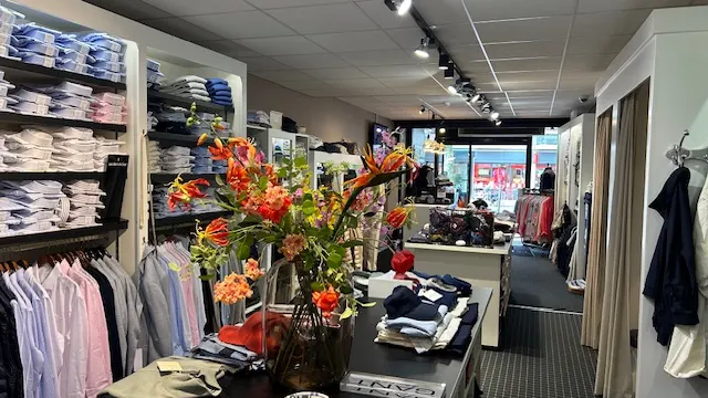 Interieur van De Lord Mannenmode met overhemden, truien en een boeket bloemen