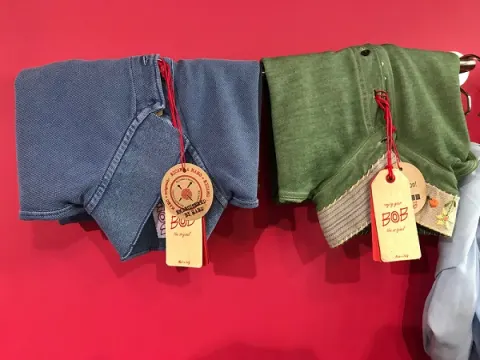 Korte broeken van BoB in blauw en groen tegen een rode wand