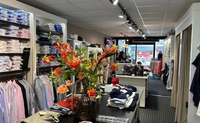 Interieur van de winkel met overhemden en een boeket bloemen